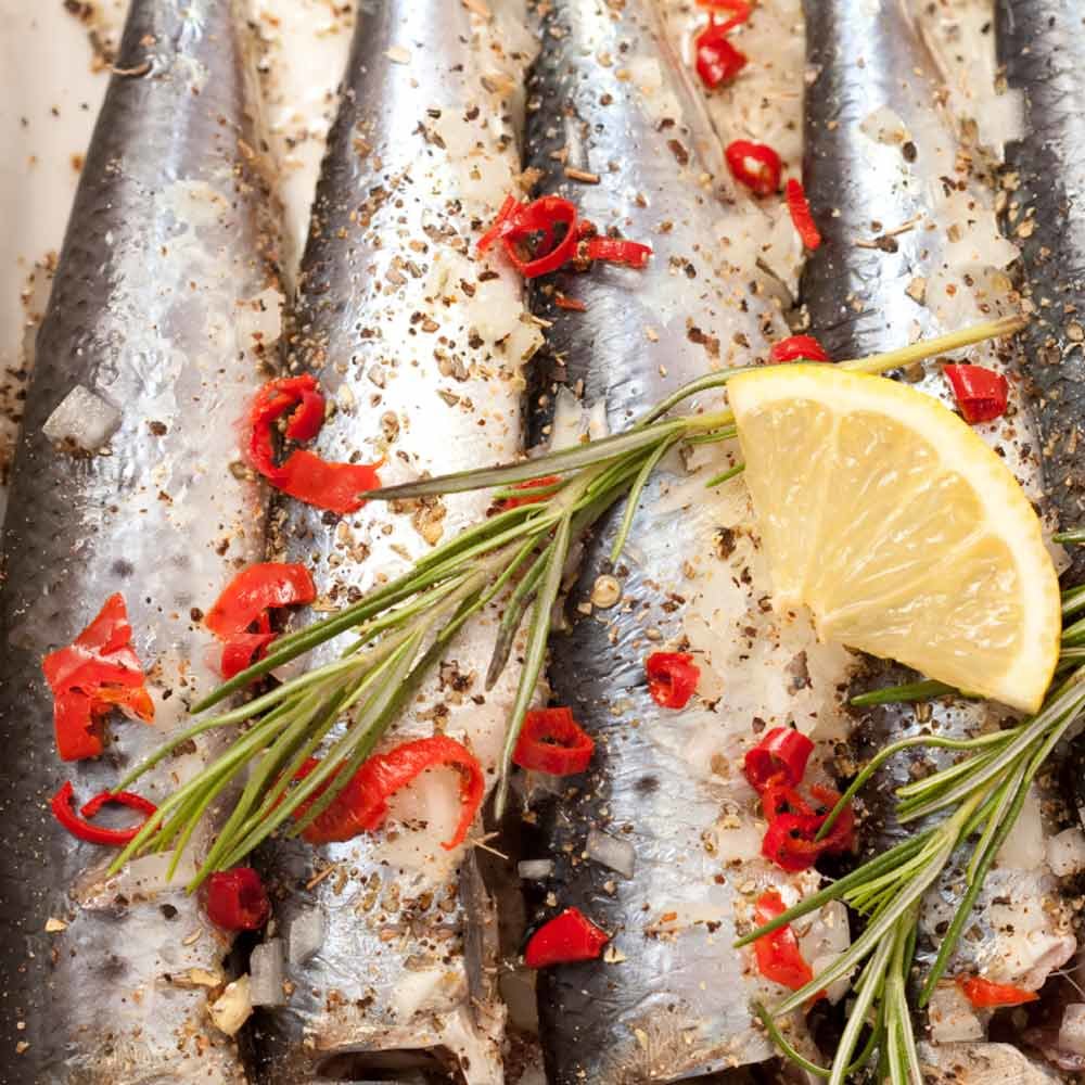 Pikante Sardinenfilets in Olivenöl – mit passenden Accessoires arrangiert