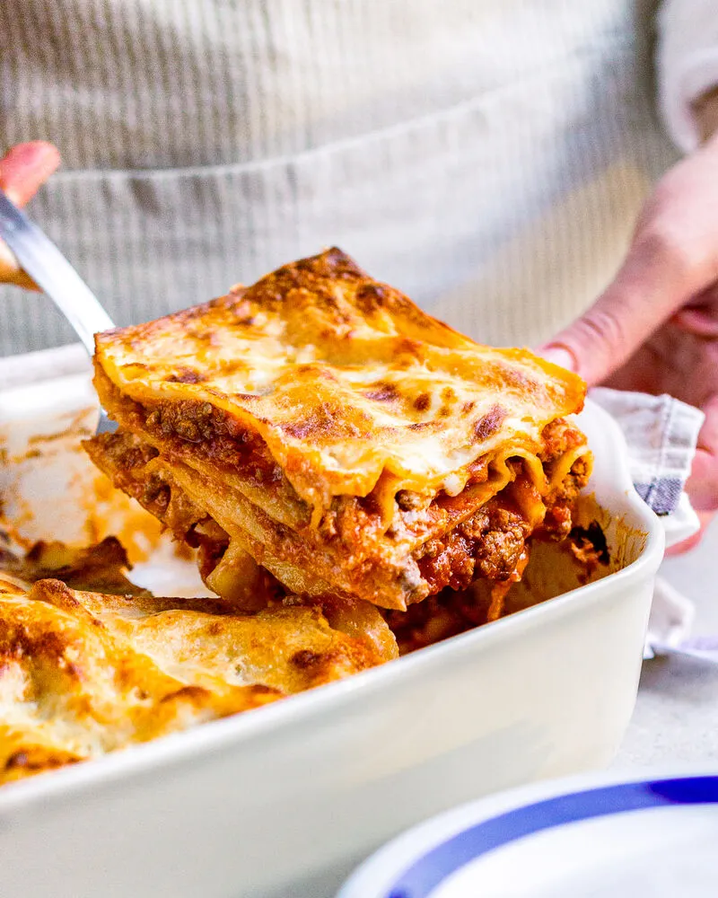 Frische Lasagneplatten frische Lasagneplatten zum Kochen, Hand hebtmit einem Pfannenwender die fertige Lasagne aus der Ofenform