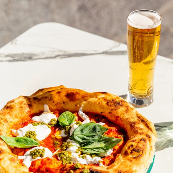 eine neapolitanische Pizza auf einem weißen sonnenbeschienenen Tisch in Neapel