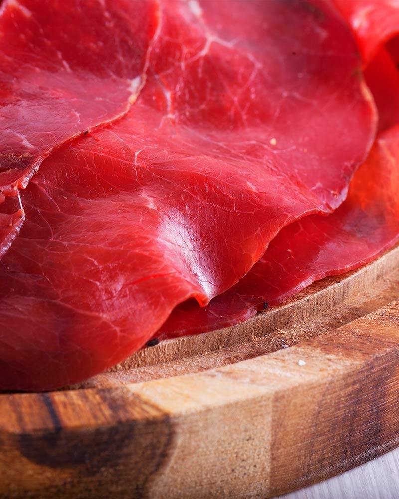 Bresaola vom Chianina - am Stück – mit passenden Accessoires arrangiert