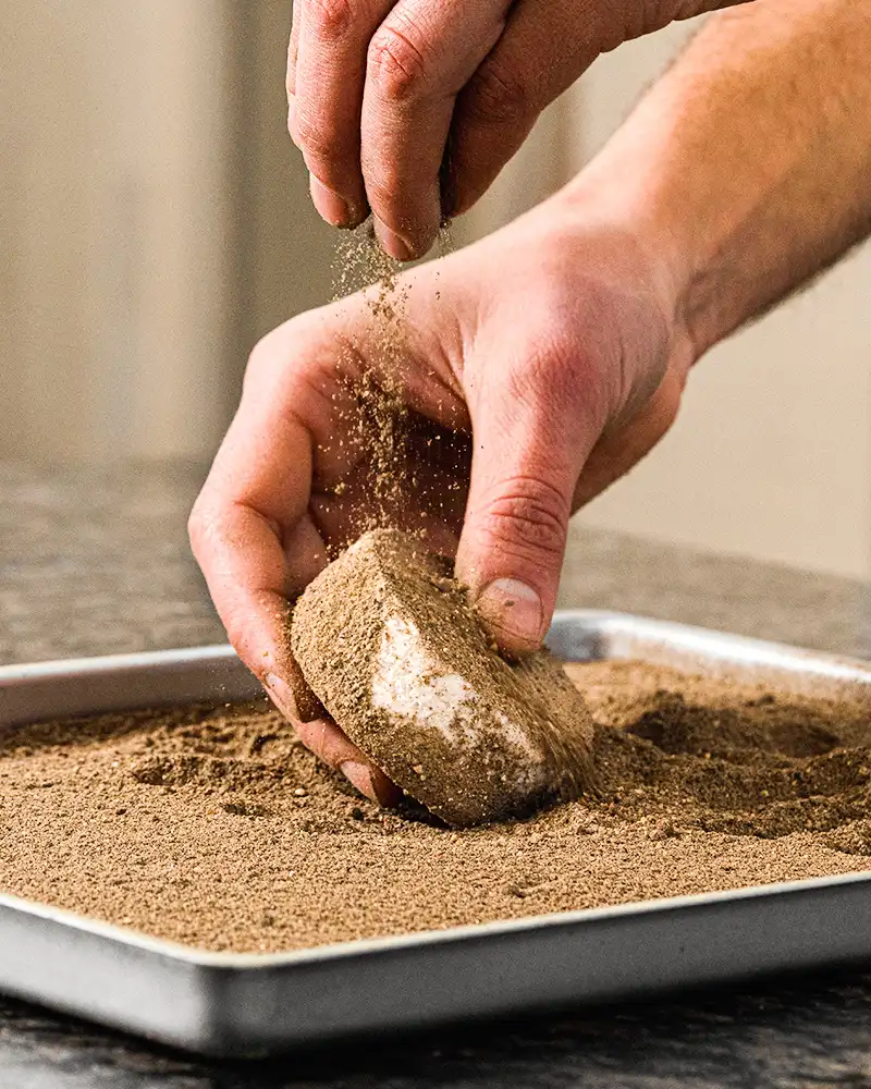 vegane Käsealternative wird mit Pfeffer ummantelt