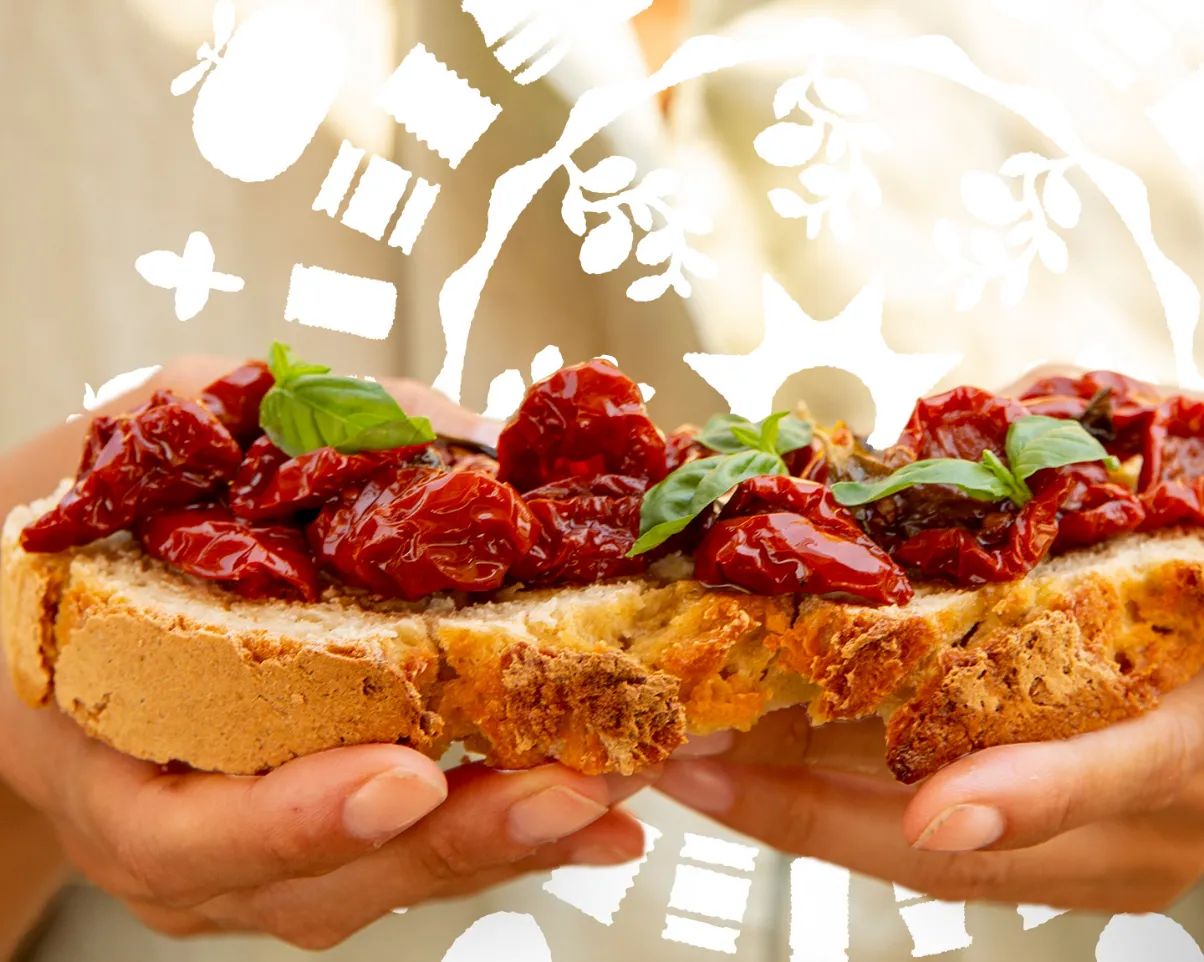 getrocknete Tomaten für Bruschetta zwei Hände halten jeweils ein Bruschetta Brot reich belegt mit getrockneten Tomaten
