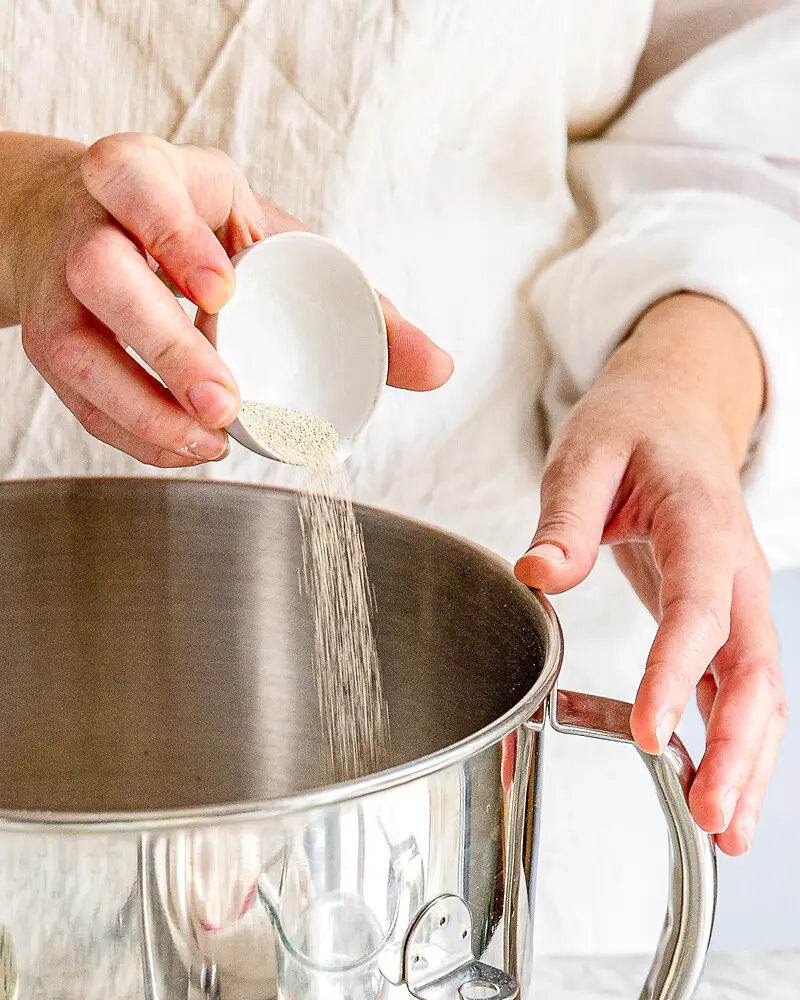 Hand kippt Trockenhefe in Schüssel