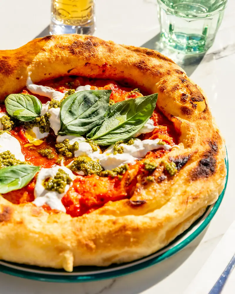 eine klassische Pizza Margherita liegt auf einem Teller